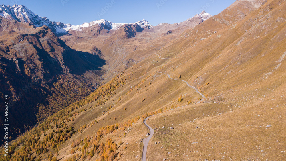 Road to the Gavia mountain pass in Italy. Amazing aerial view of the mountain bends creating beautiful shapes. Fall time. Warm colors. Nobody on the road