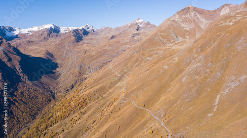 Road to the Gavia mountain pass in Italy. Amazing aerial view of the mountain bends creating beautiful shapes. Fall time. Warm colors. Nobody on the road