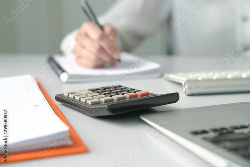 Office table view with Accountant or Woman Executive out of focus and focus is on calculator