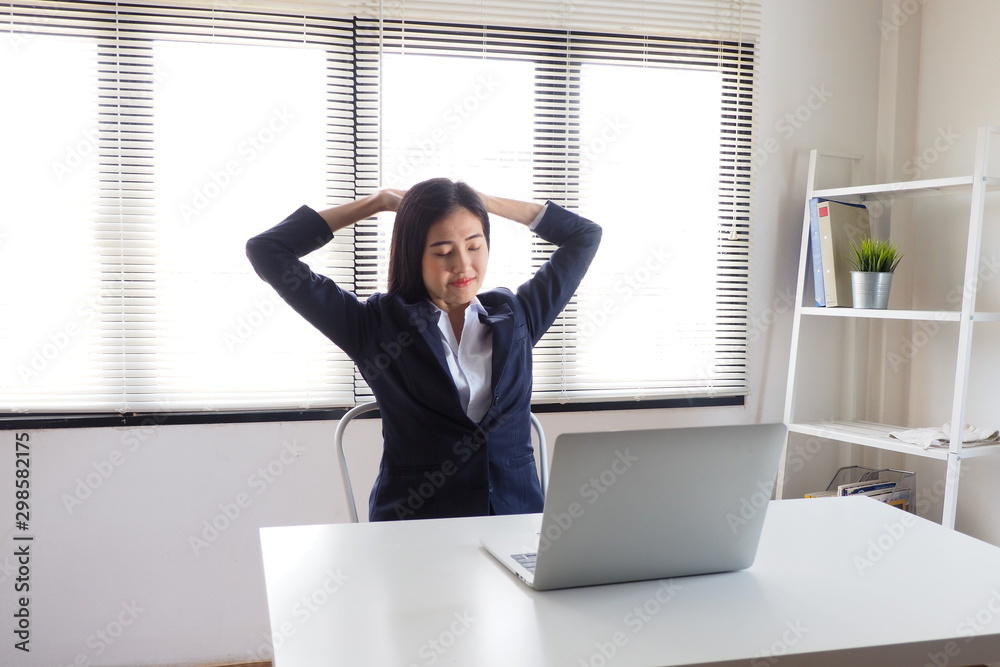 Young Asian female sitting at her desk stretching her hands and arms for relaxation after working long time in front of her laptop to avoid office syndrome problem. Healthcare and working lifestyle Young Asian female sitting at her desk stretching her hands and arms for relaxation after working long time in front of her laptop to avoid office syndrome problem. Healthcare and working lifestyle