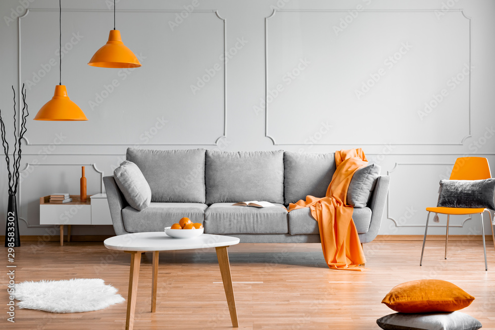 Orange lamp above grey scandinavian sofa in modern interior - obrazy, fototapety, plakaty 