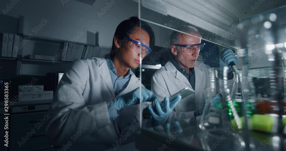 Portrait of two male scientists are making an analysis of the DNA and molecules in the test tubes and signs results in laboratory. Portrait of two male scientists are making an analysis of the DNA and molecules in the test tubes and signs results in laboratory.