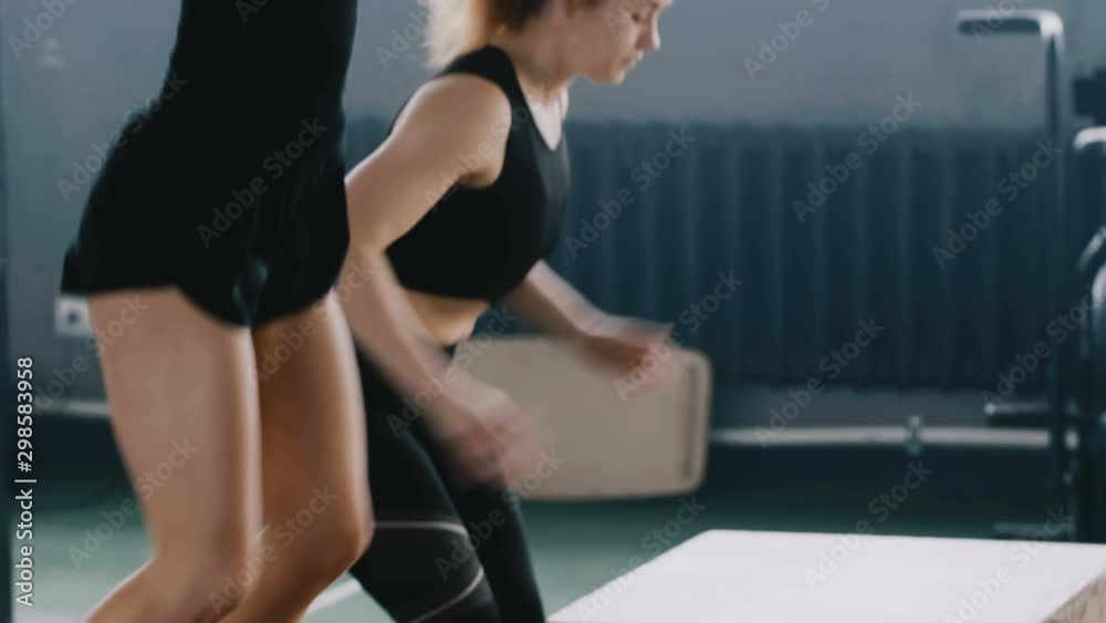 Side view close-up young attractive blonde woman working out with personal female fitness instructor in gym slow motion. Side view close-up young attractive blonde woman working out with personal female fitness instructor in gym slow motion.