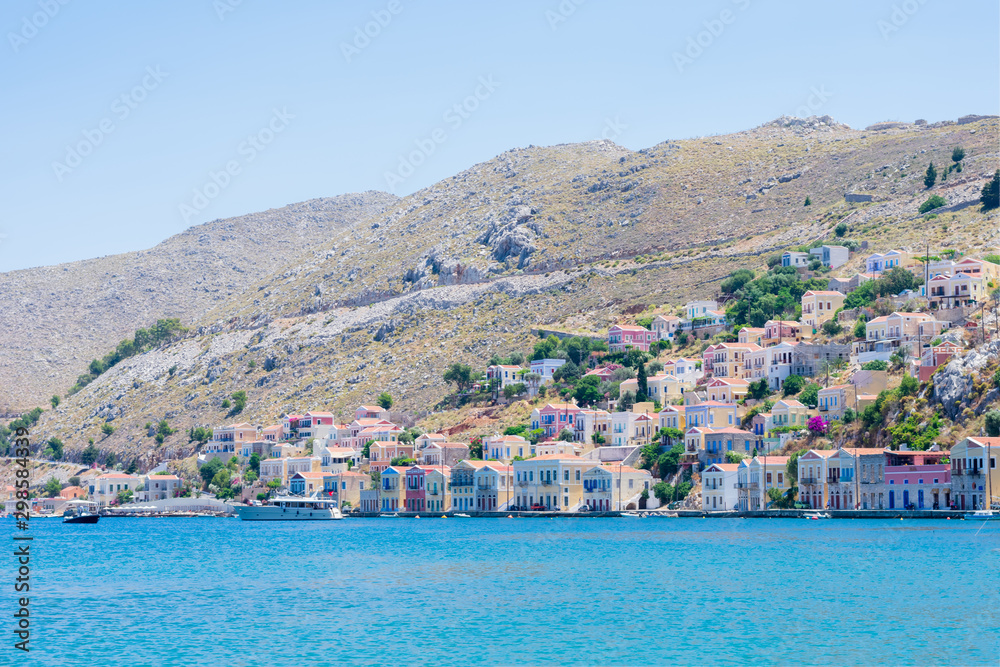 Picturesque view on tiny colorful houses on rocks near the Mediterranian sea on Greek island in sunny summer day, vacation on exotic islands
