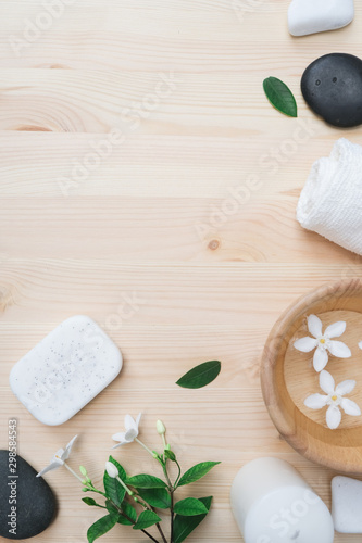Flat lay Spa composition with body care items on wood background. Sea salt in bowl, towels, scrub, aroma oil in bottles and flowers.