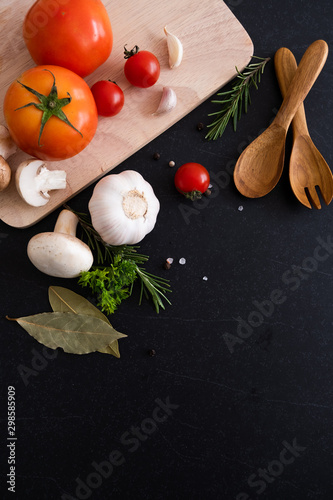 spices herbs and greens. Ingredients for cooking. Food background on black slate table. Top view copy space. Rosemary, tomatoes, garlic and peppers. - Image