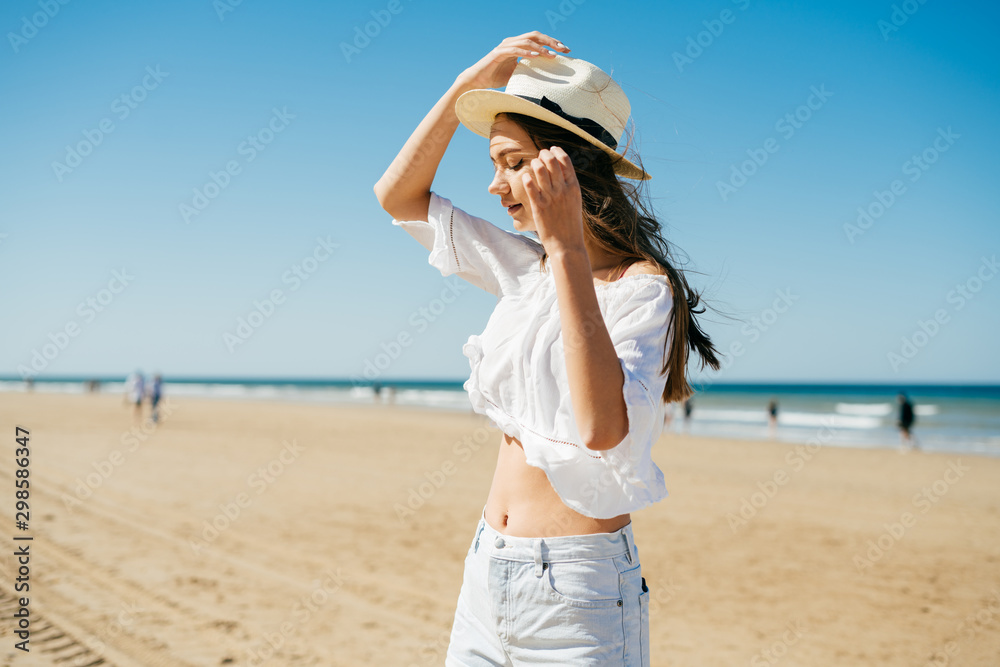girl holds a hat from the wind on the beach girl holds a hat from the wind on the beach