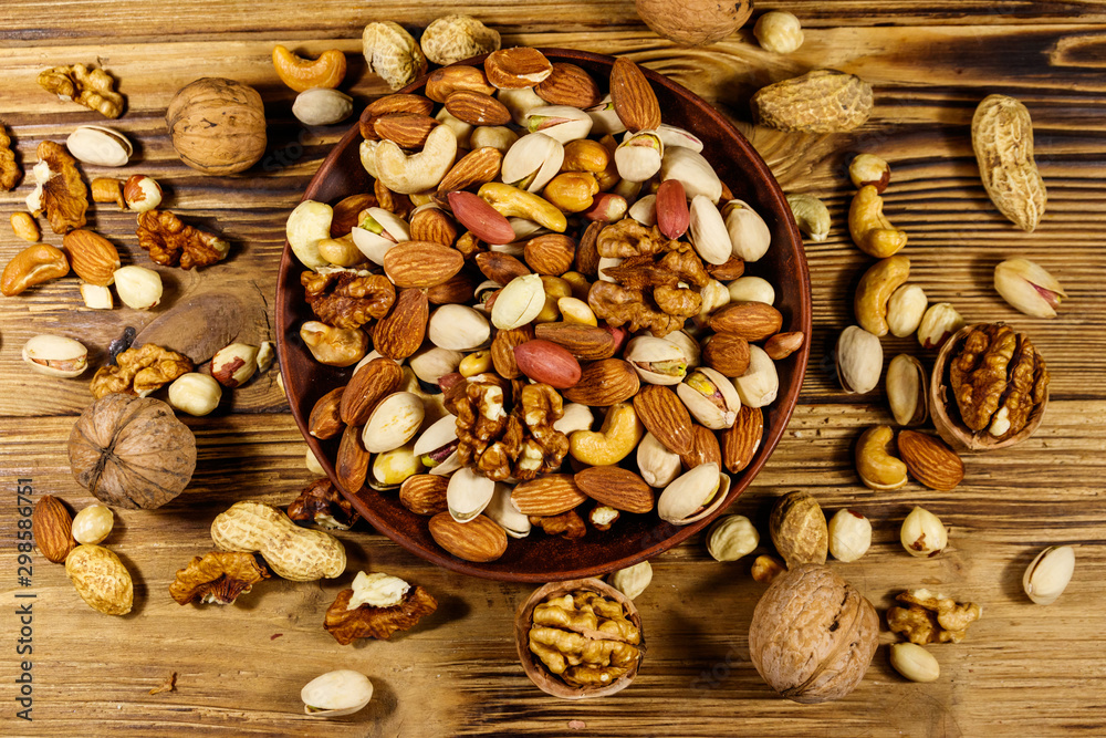 Mixed nuts on wooden table. Walnuts, pistachio, almond, peanut, cashew, hazelnut in ceramic bowl. Healthy eating concept. Top view Mixed nuts on wooden table. Walnuts, pistachio, almond, peanut, cashew, hazelnut in ceramic bowl. Healthy eating concept. Top view