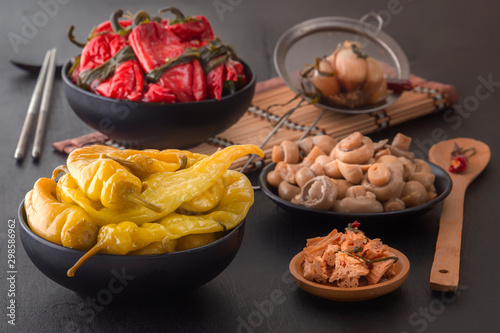 Fermented products red and green hot peppers, mushrooms on a black table - traditional Korean food. Copy space
