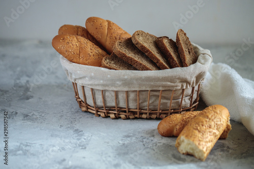 Fresh bread baguette with sesame seeds and slices of rye bread are in the breadbox on the table. Bakery. Flat lay. Close-up, minimalism. photo