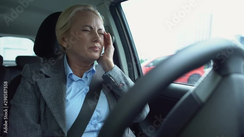 Aged businesswoman feeling strong migraine, sitting on drivers seat, health care