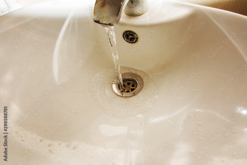 Water flows from the tap. Dirty washbasin and drain hole Water flows from the tap. Dirty washbasin and drain hole
