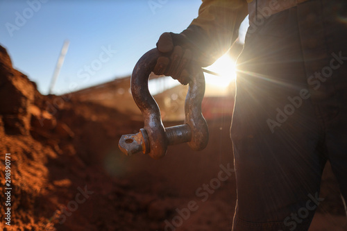 Rigger wearing a safety glove holding crane lifting 17 tone shackle with defocused crane at the back ground during sunset construction site Sydney, Australia photo