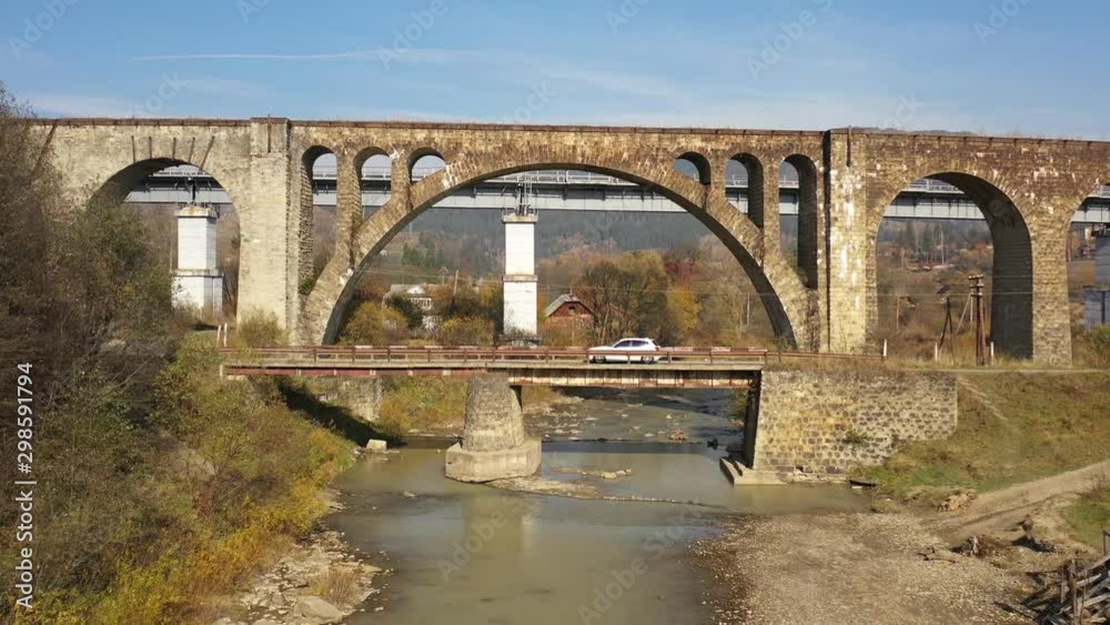 Old railway bridge trough the mountain river. Car driving on the bridge Old railway bridge trough the mountain river. Car driving on the bridge