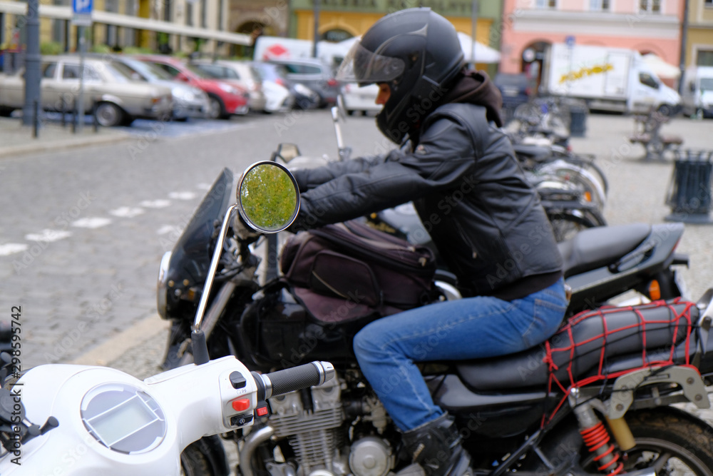 White urban scooter and defocused woman on a powerful black motorcycle in a parking in the tourist center of the city. Scooter handle control close-up.