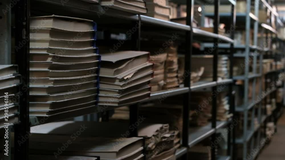 Bookshelves in an old library or archive room. Old room with books and documents with a basement light. Footage for the concept of training and historical news. Bookshelves in an old library or archive room. Old room with books and documents with a basement light. Footage for the concept of training and historical news.