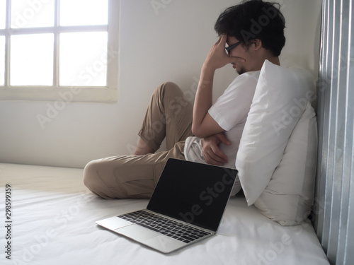 Stressed exhausted young Asian man with laptop in depression.