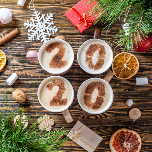 Fototapeta Naklejka Na Ścianę i Meble -  Card with numbers 2020 for New year and Christmas. Cup of coffee with figures on wooden background. Top view. Flat lay