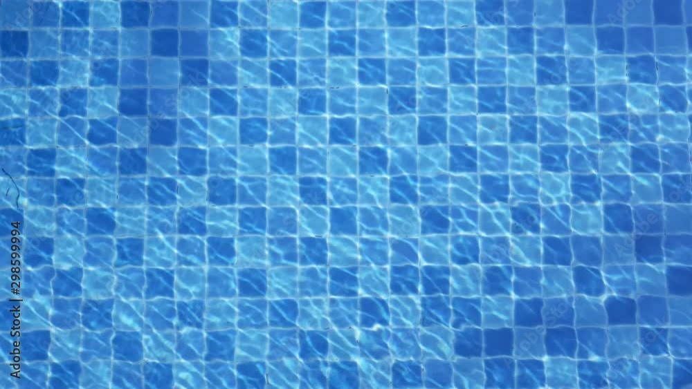 The sun's rays play in the clear water of the blue pool. Water texture in the sunlight. The sun's rays play in the clear water of the blue pool. Water texture in the sunlight.