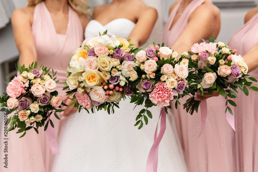 Bride and bridesmaids in pink dresses posing with bouquets at wedding day. Happy marriage and wedding party concept