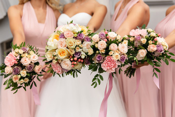 Bride and bridesmaids in pink dresses posing with bouquets at wedding day. Happy marriage and wedding party concept