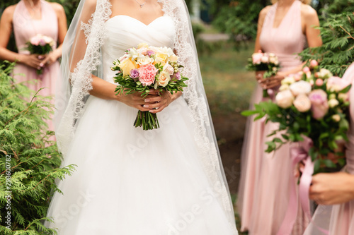 Bride and bridesmaids in pink dresses posing with bouquets at wedding day. Happy marriage and wedding party concept