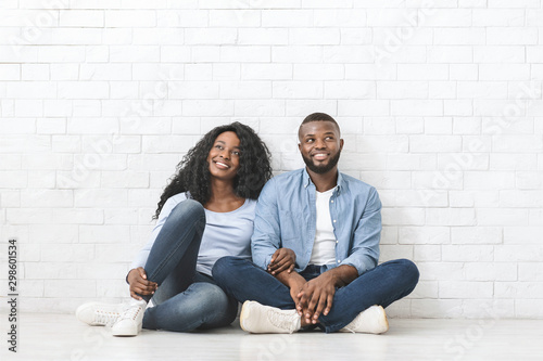 Dreamy black couple sitting on floor, planning interior © Prostock-studio