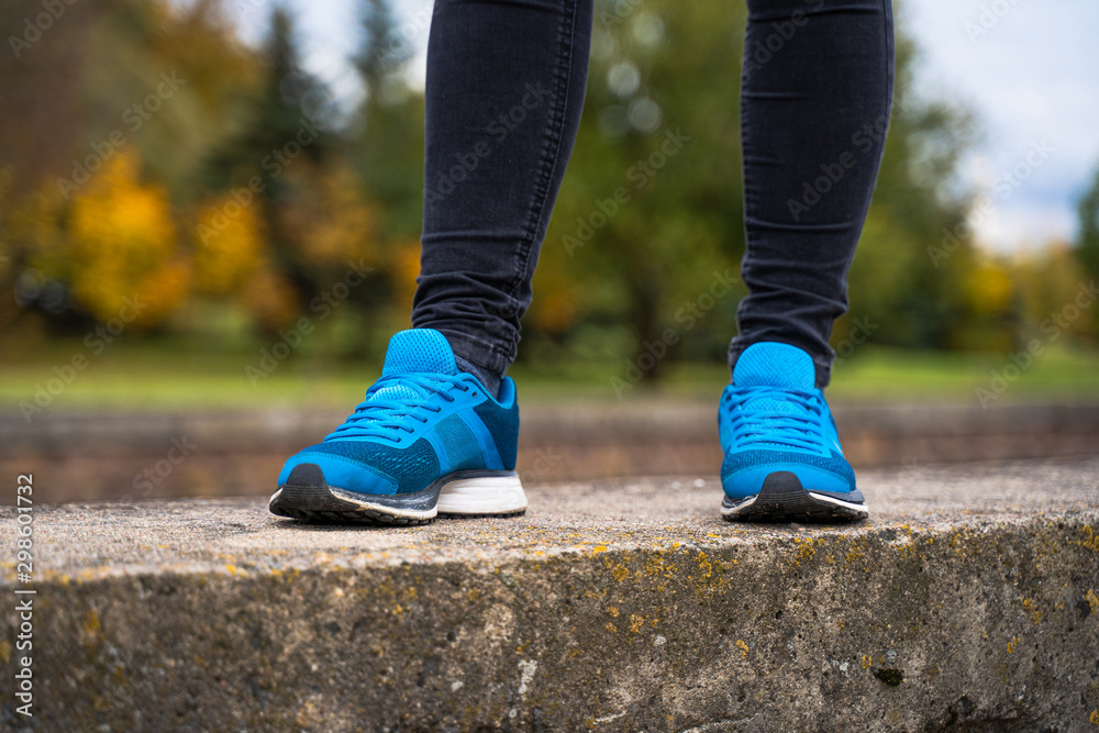Blue sneakers on a woman legs. Outside workout in running shoes concept Blue sneakers on a woman legs. Outside workout in running shoes concept