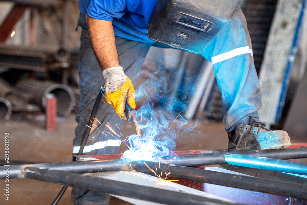Metal worker is welding metals with protection of him self Metal worker is welding metals with protection of him self