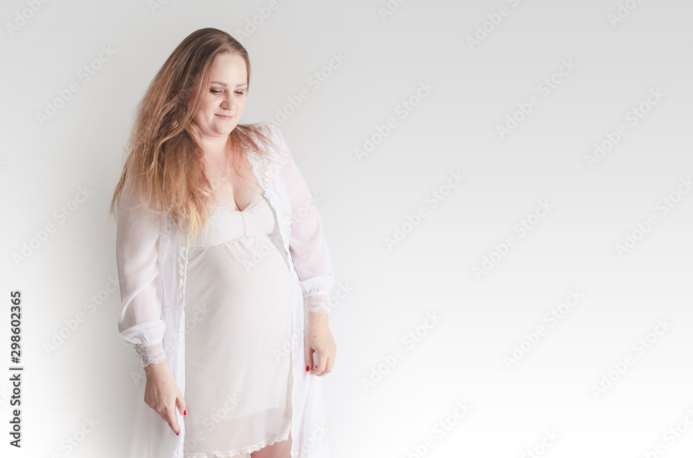 Young pregnant woman in pajamas, studio portrait on gray. Copy space Young pregnant woman in pajamas, studio portrait on gray. Copy space