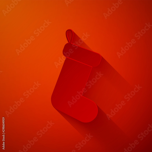 Paper cut Christmas sock icon isolated on red background. Paper art style. Vector Illustration