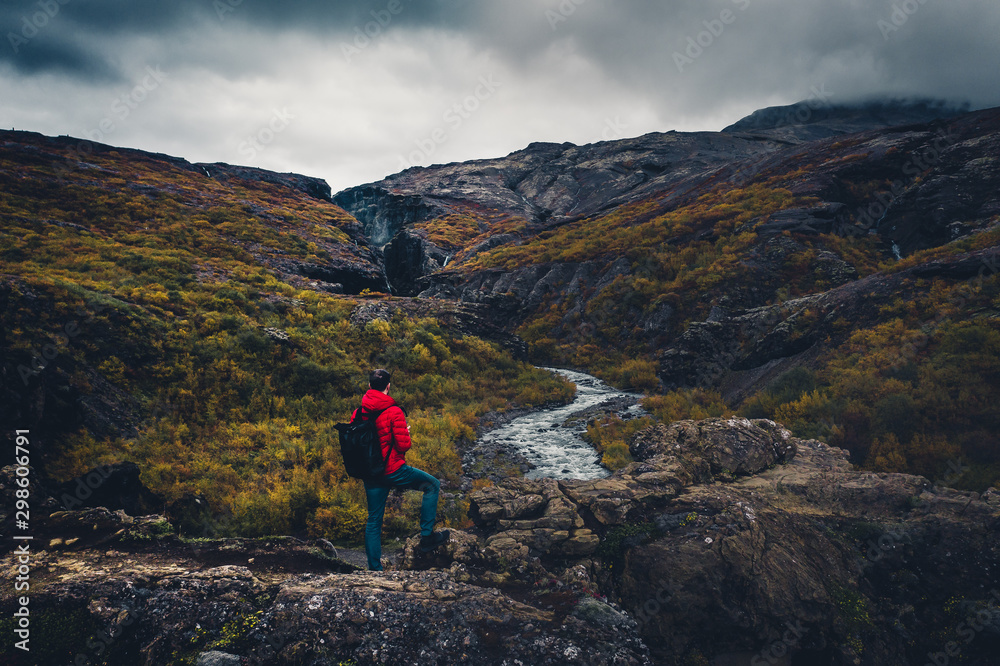 Man in red jacket watching the river in Iceland