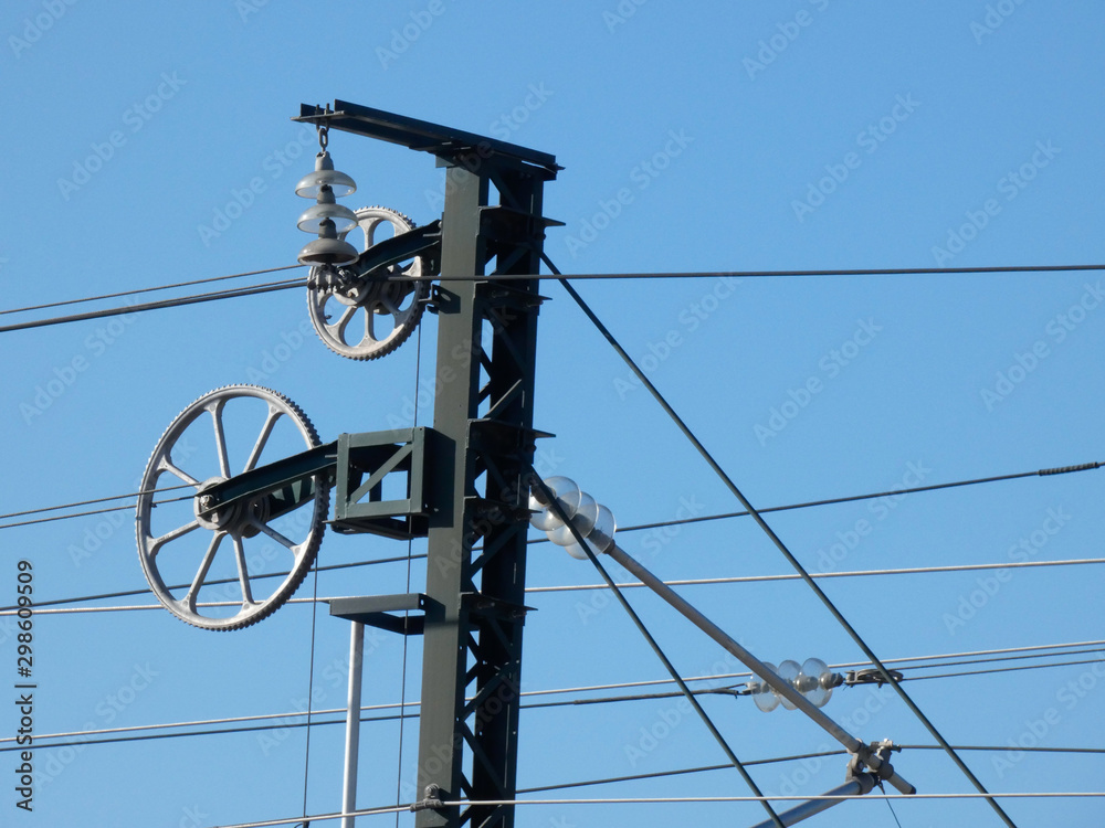 Catenaria y cables en la vía del tren, Cables electricos que hacen llegar la electricidad al tren, Cielo azul y tecnología en las vías del tren. Catenaria y cables en la vía del tren, Cables electricos que hacen llegar la electricidad al tren, Cielo azul y tecnología en las vías del tren.