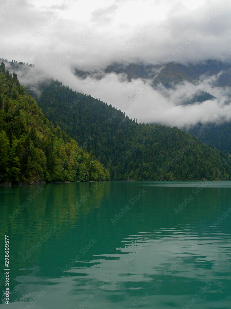 Alpine lake Ritsa. Abkhazia. Summer view on a cloudy day of the lake in the wooded mountains. Alpine lake Ritsa. Abkhazia. Summer view on a cloudy day of the lake in the wooded mountains.