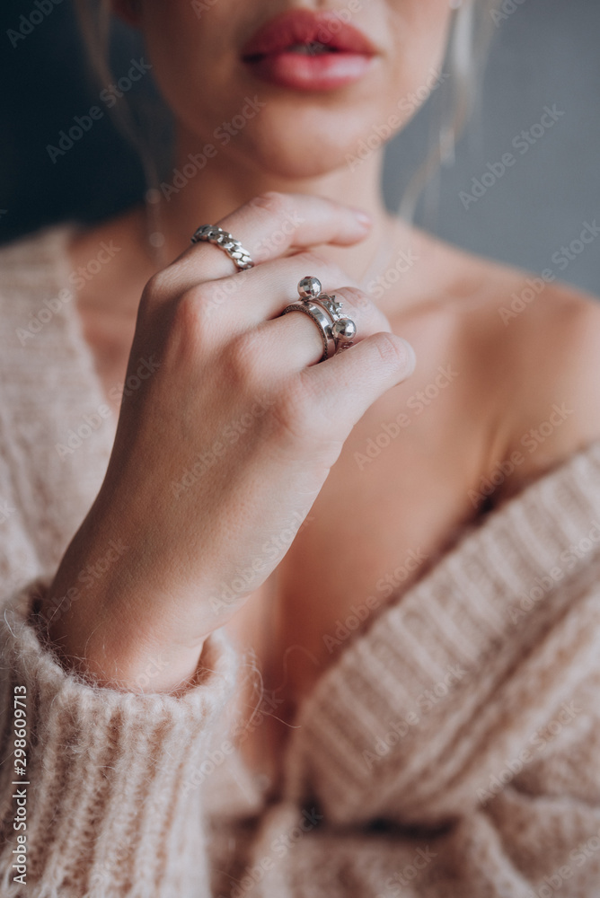 a girl in a beige jacket shows rings on her hands