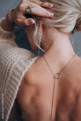 beautiful girl with bare back shows off pendant and rings