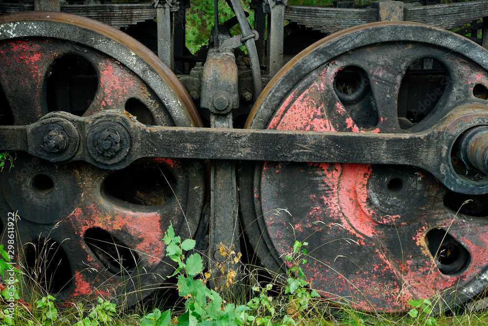 Big rusty wheels of an old steam locomotive in the forest