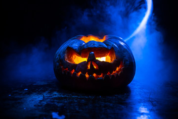 Close up view of scary Halloween pumpkin with eyes glowing inside at black background. Selective focus