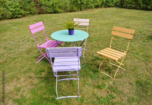 Beautiful colored vintage chairs and garden table outdoor on a green grass © Sinuswelle