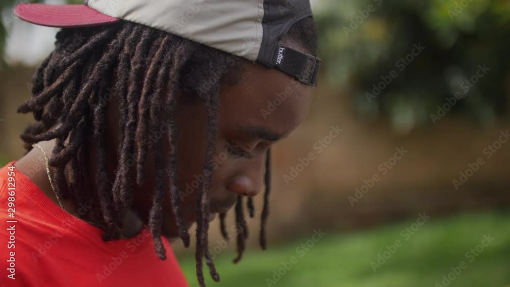 Close up view head of skateboarder with dreads on his head using cell phone