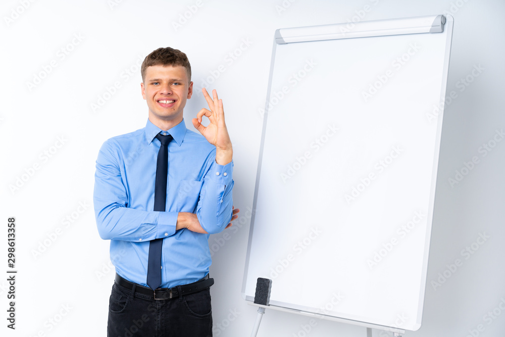 Young businessman giving a presentation on white board showing ok sign with fingers Young businessman giving a presentation on white board showing ok sign with fingers