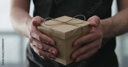 young man shows brown craft paper gift box
