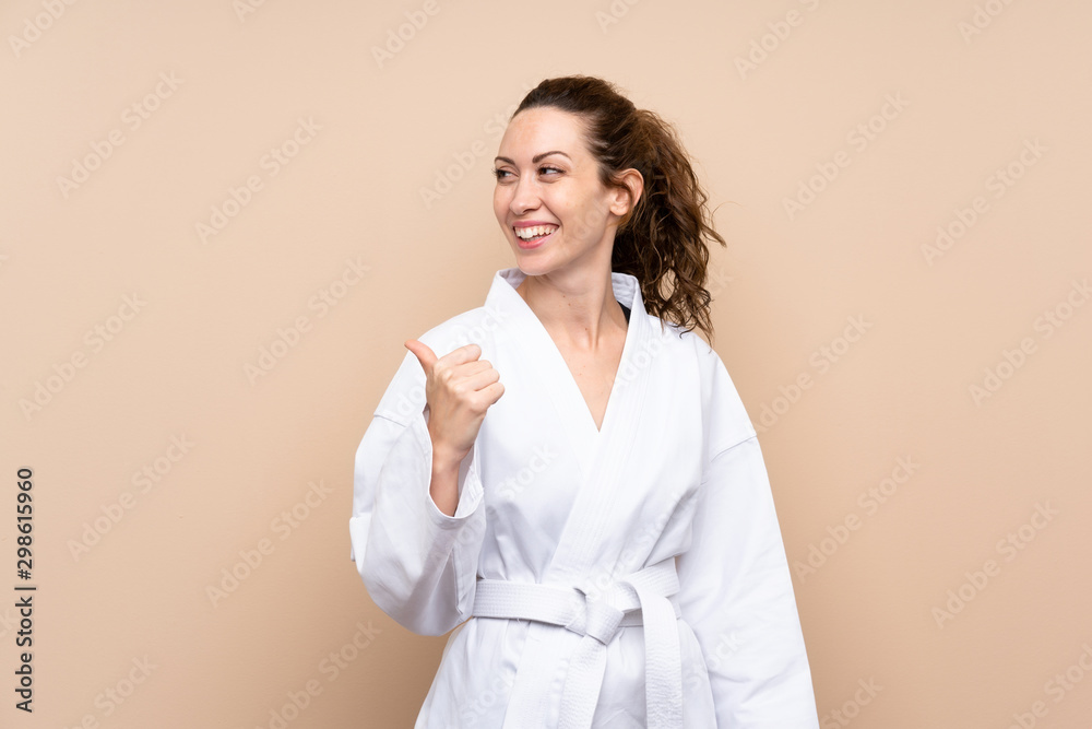 Young woman doing karate pointing to the side to present a product Young woman doing karate pointing to the side to present a product