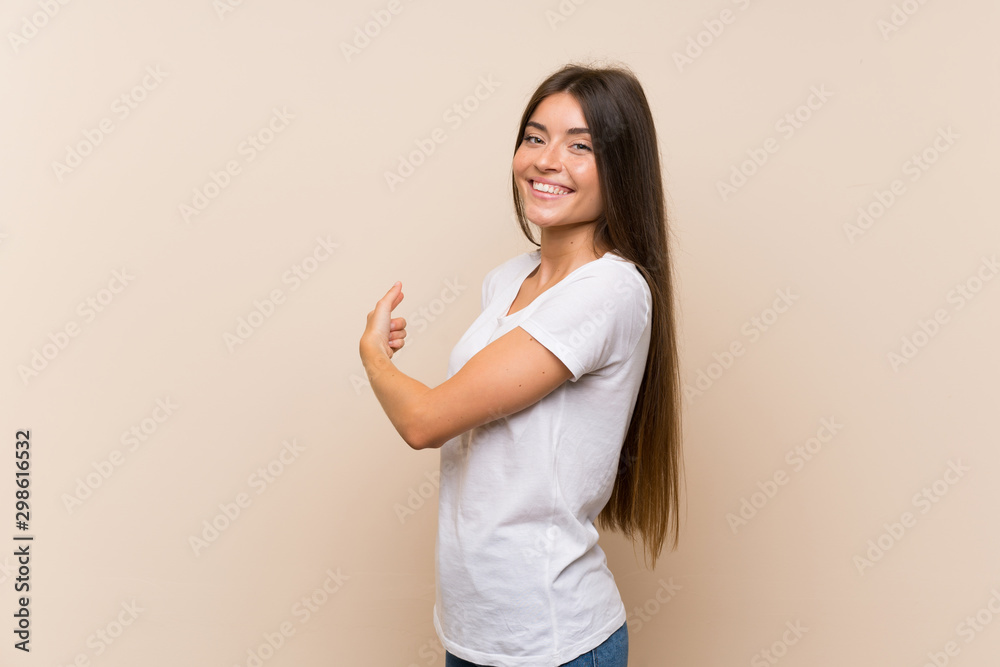 Pretty young girl over isolated background pointing back Pretty young girl over isolated background pointing back