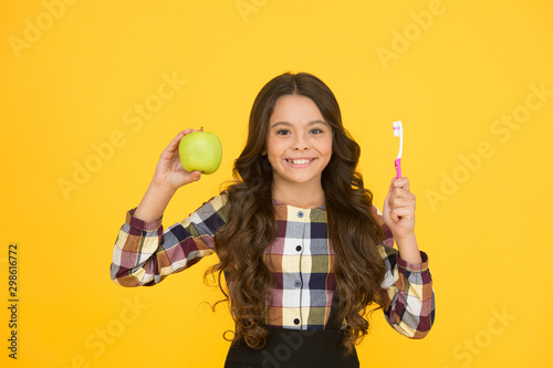 Beautiful natural smile. Happy child hold green apple and toothbrush. Little girl smile with brush and natural fruit. Natural dental care. Gentle natural way to white teeth