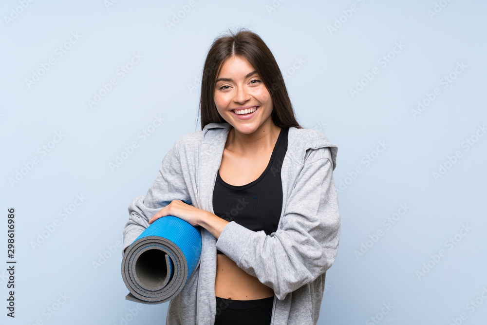 Young sport girl with mat over isolated blue background Young sport girl with mat over isolated blue background