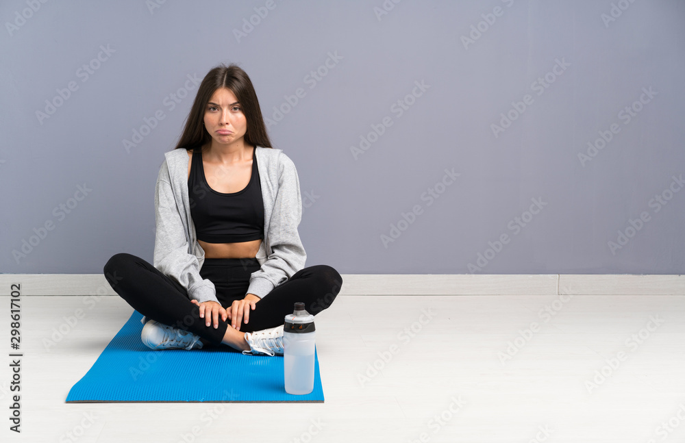 Young sport woman sitting on the floor with mat sad Young sport woman sitting on the floor with mat sad