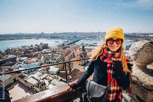 Young smiling girl on the background of the panorama of Istanbul on sunny spring day. girl in yellow hats looks at Istanbul from the observation deck of the Galata Tower. clear autumn day in istanbul