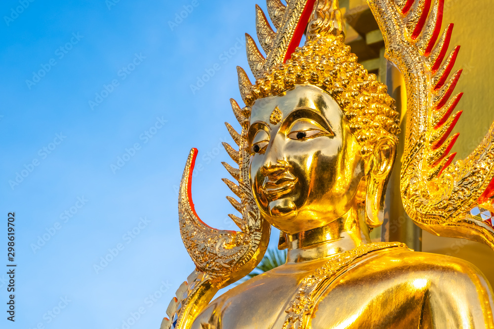 The golden Buddha face and the Buddhist yellow flag in outdoor of the temple in Thailand with the blue sky copy space The golden Buddha face and the Buddhist yellow flag in outdoor of the temple in Thailand with the blue sky copy space