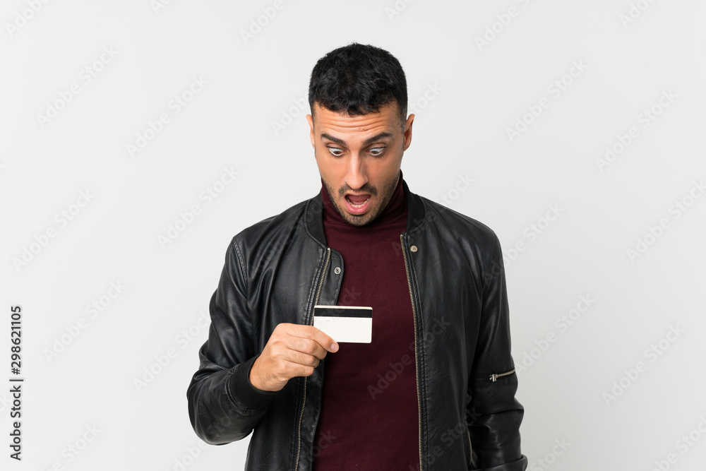 Young man over isolated white background holding a credit card Young man over isolated white background holding a credit card